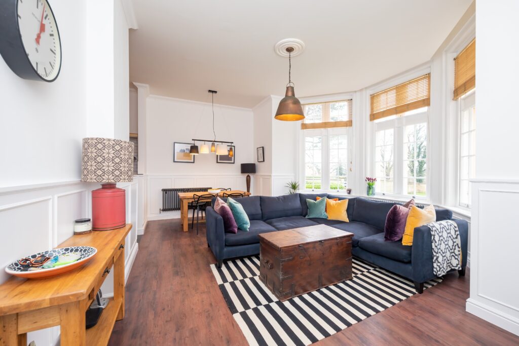 Professional photo of living room with corner sofa, dining table and bay windows